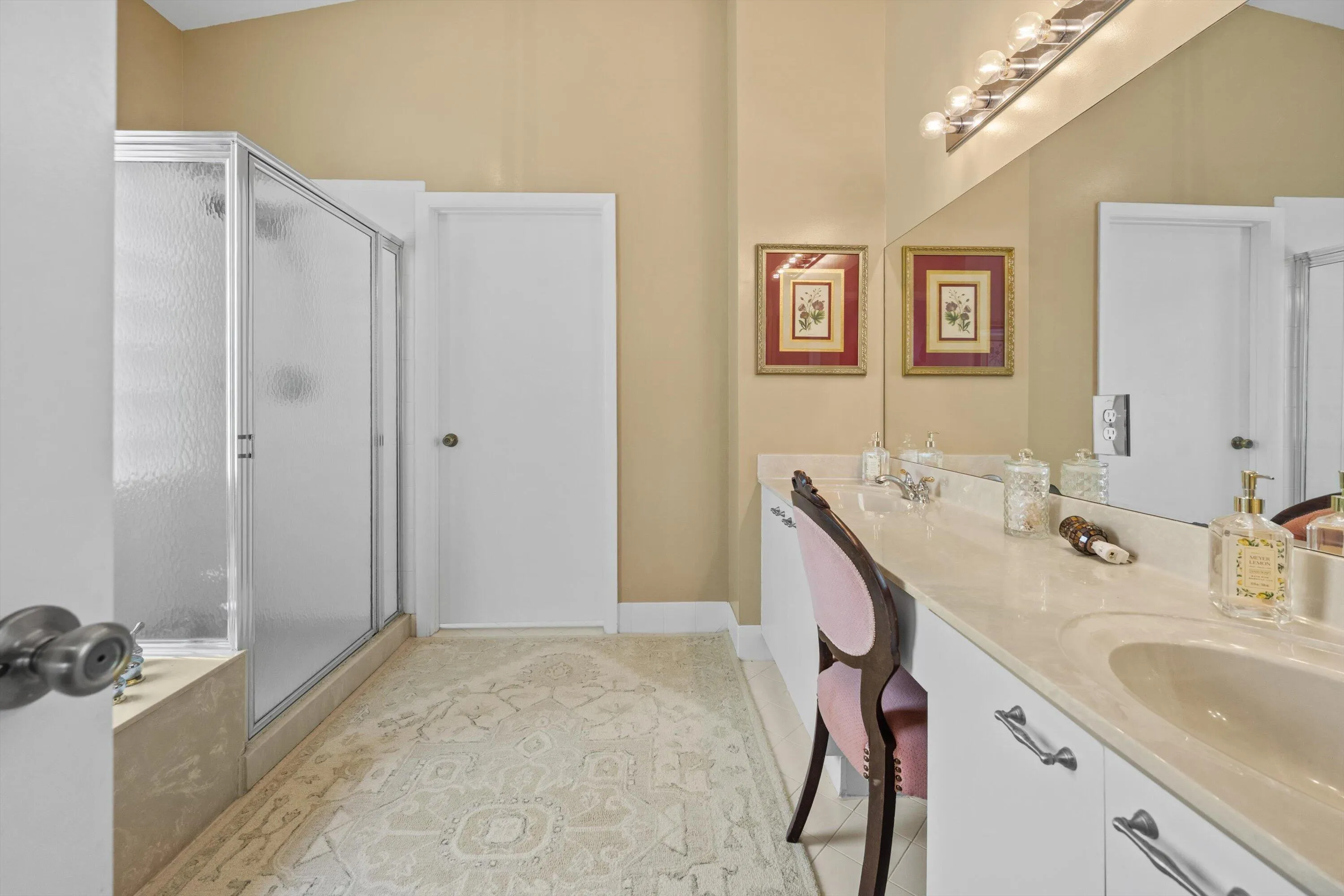 Dual vanity with integrated sinks, expansive counter space, large mirror, and glass-enclosed shower