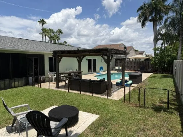 Expansive backyard featuring a swimming pool, wooden pergola, hardscaping, a privacy fence, and screened-in patio