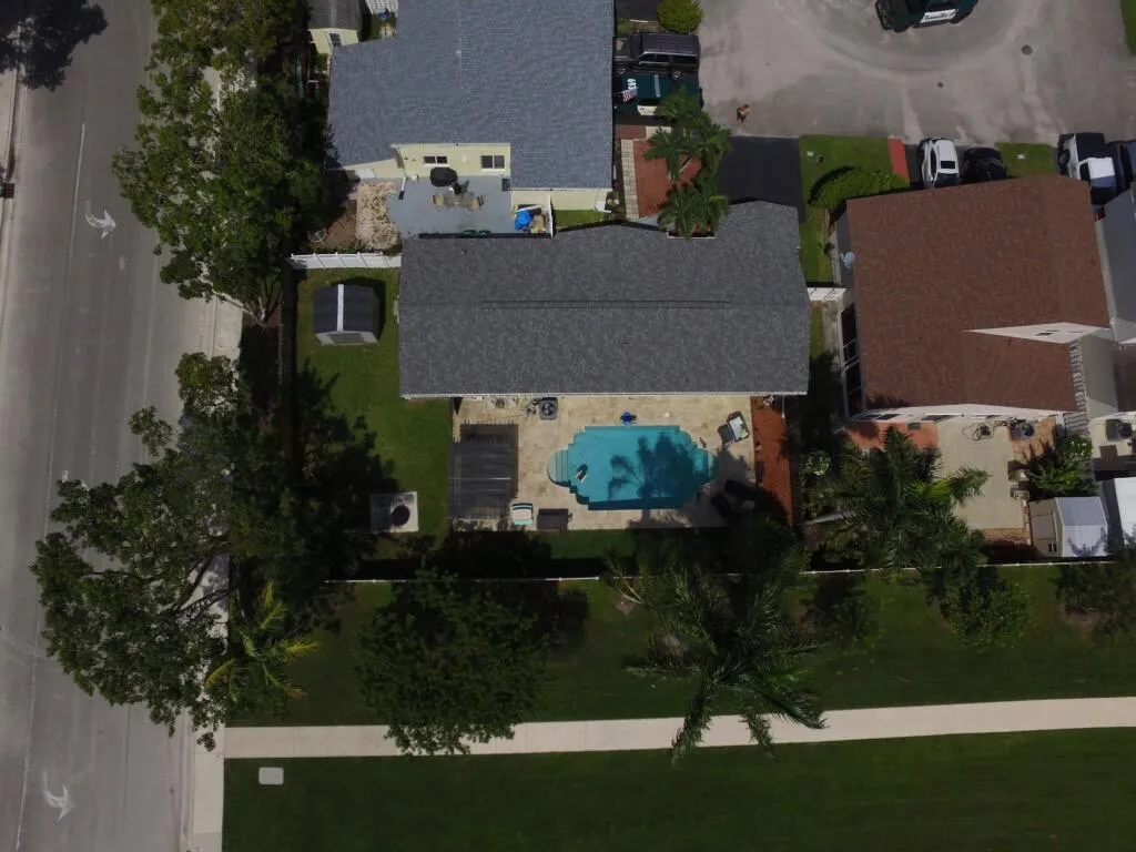 Backyard with an inground swimming pool, paved pool deck, and mature landscaping