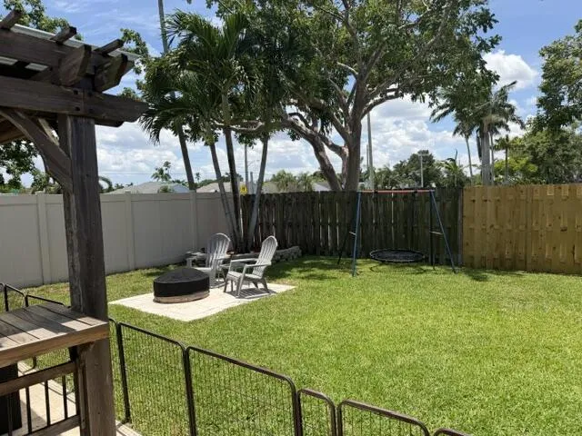 Expansive backyard featuring a manicured lawn, established perimeter fencing, and a dedicated patio area