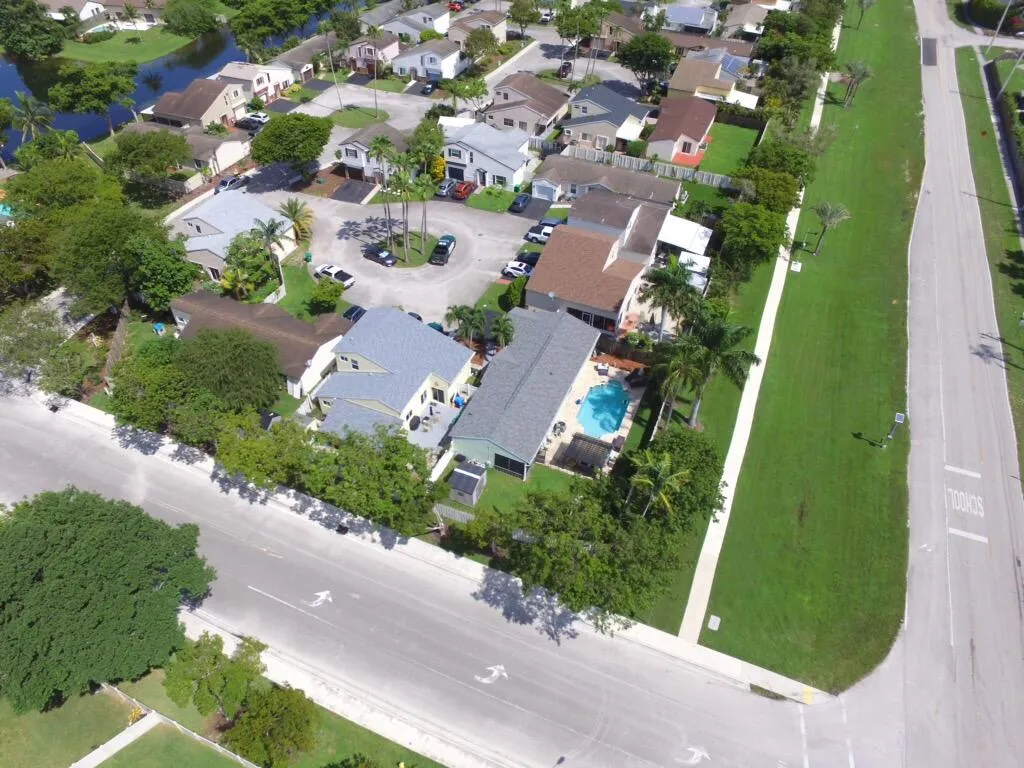Residential property with a rectangular swimming pool, mature palm trees, and a gray shingled roof
