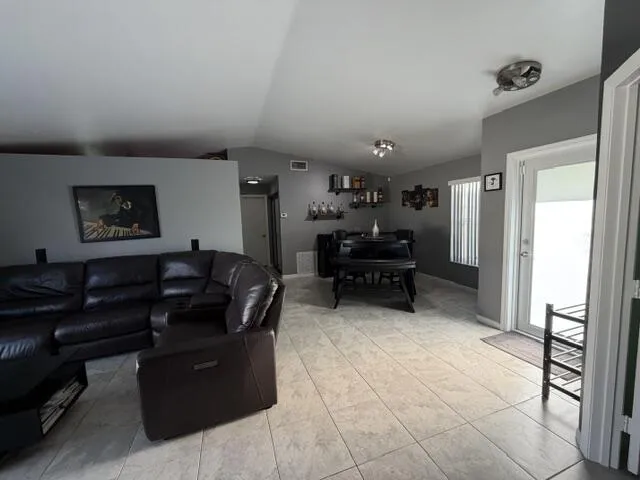 Vaulted ceilings with recessed lighting, tile flooring, and a glass-paneled exterior door