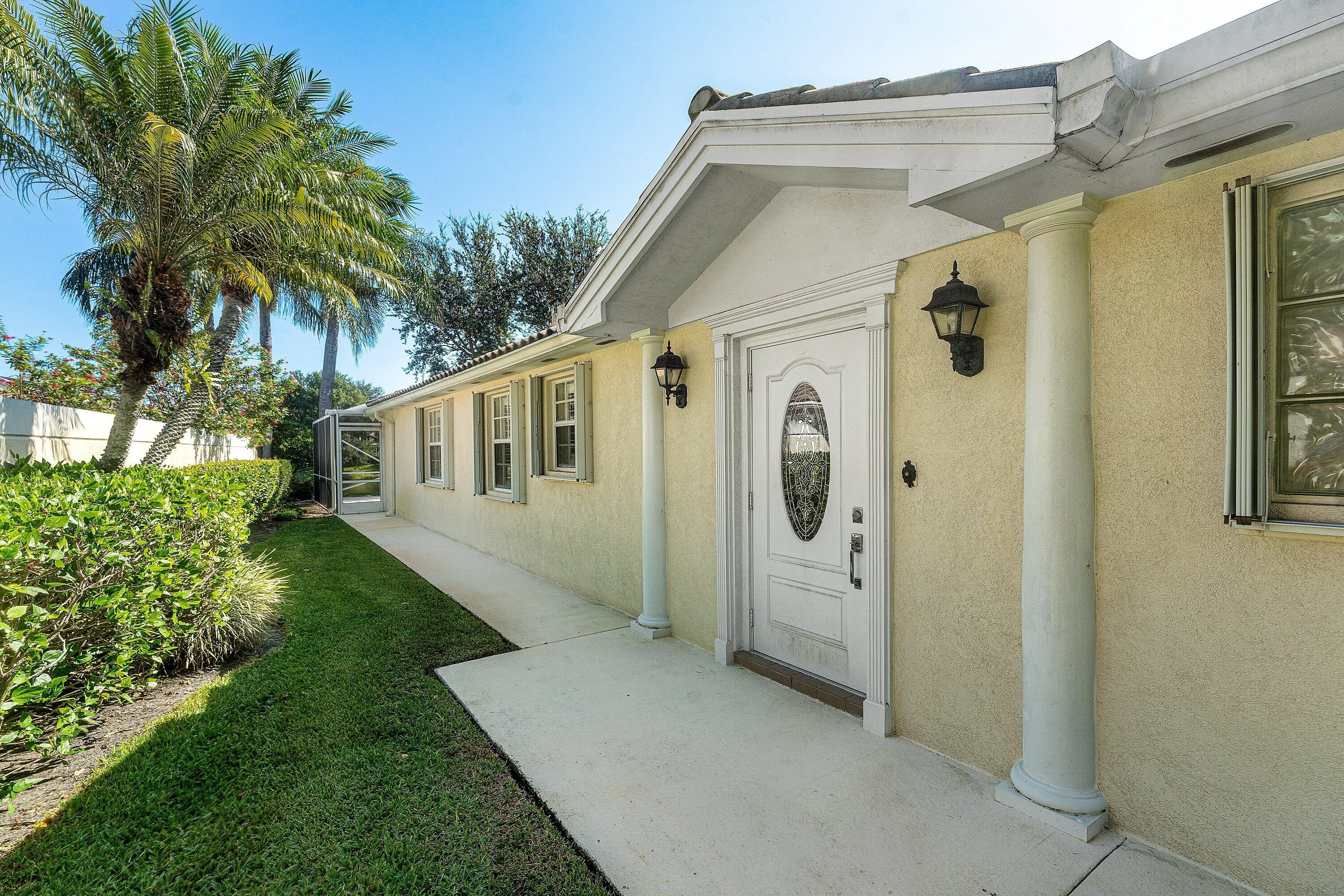 Stucco exterior featuring decorative columns, an ornate front entry door, and exterior sconces