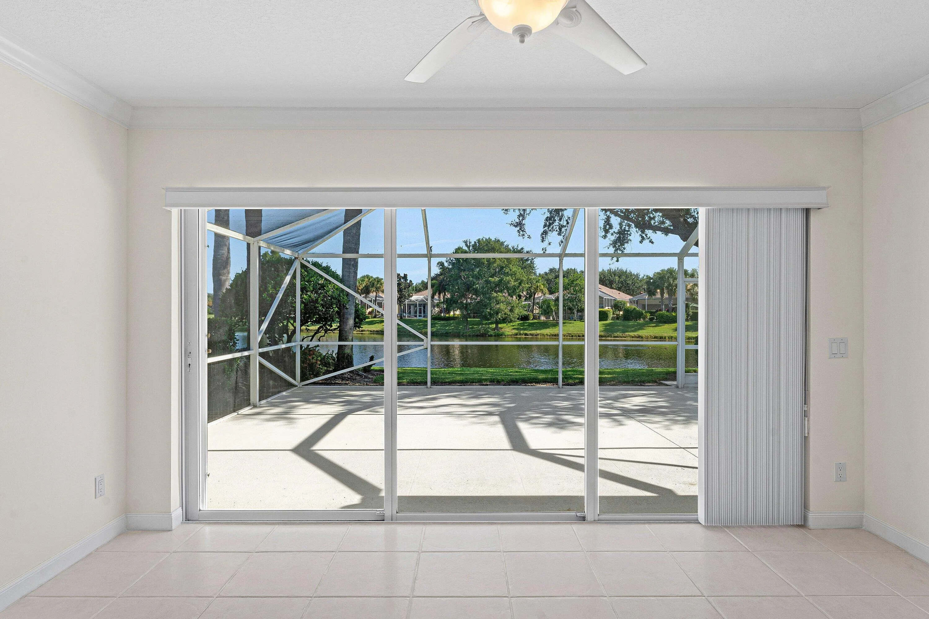 White tile flooring, crown molding, ceiling fan, expansive sliding glass doors, and a screened patio