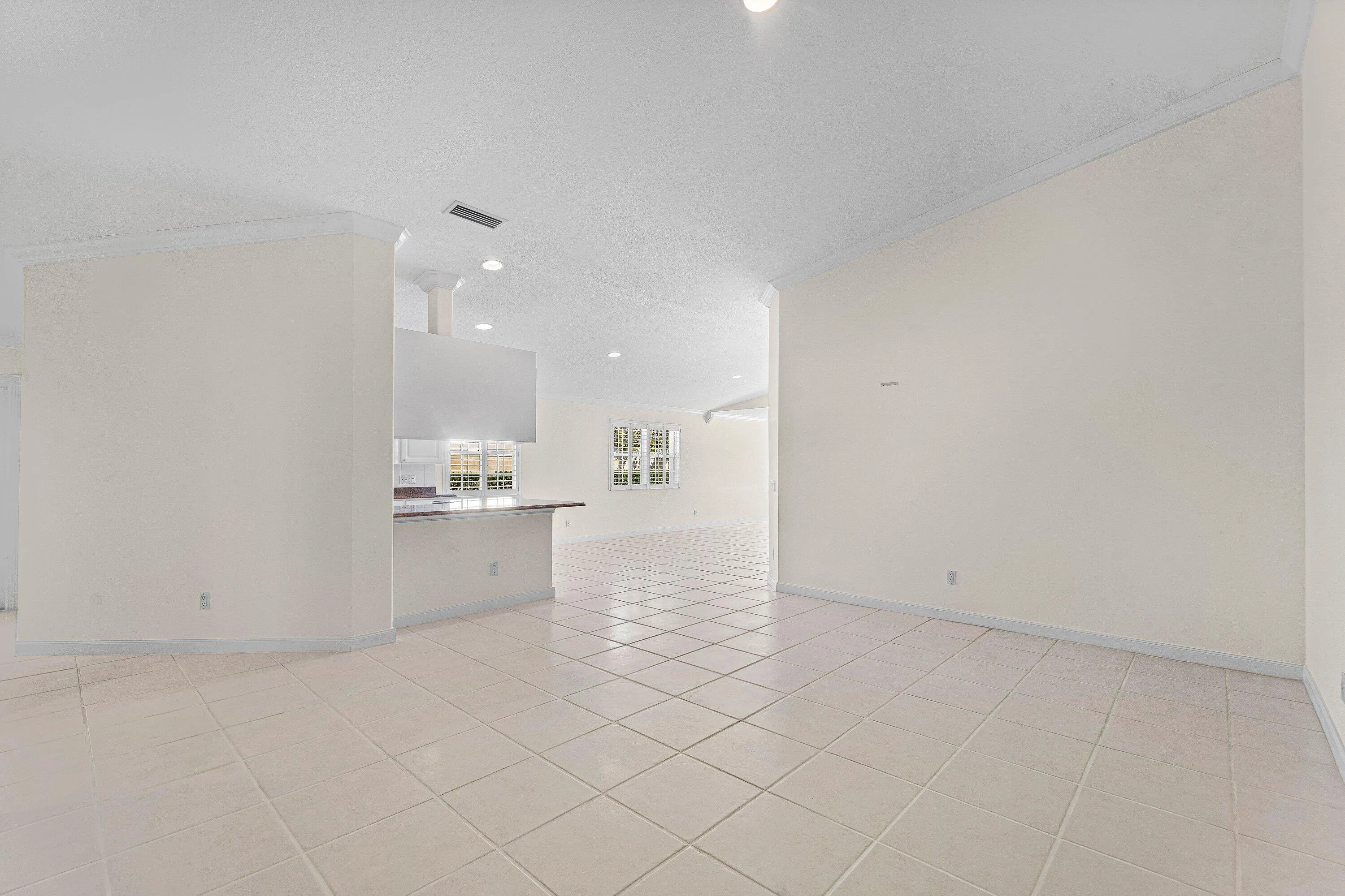 Spacious interior featuring tile flooring, crown molding, recessed lighting, and a breakfast bar