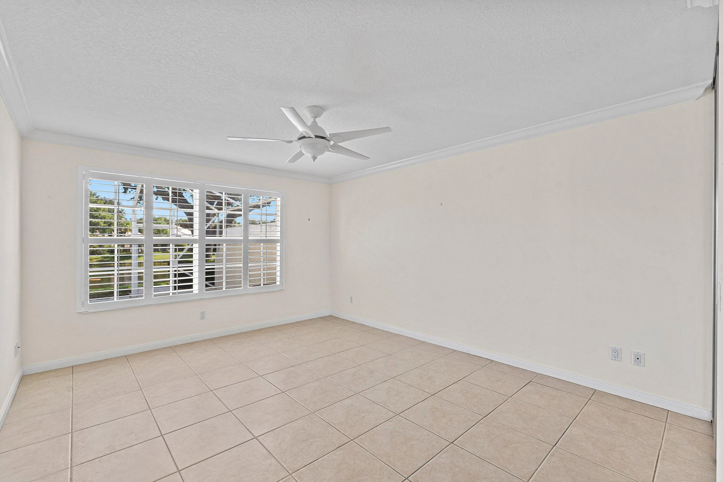 Tile flooring, white window shutters, ceiling fan, crown molding, and large window