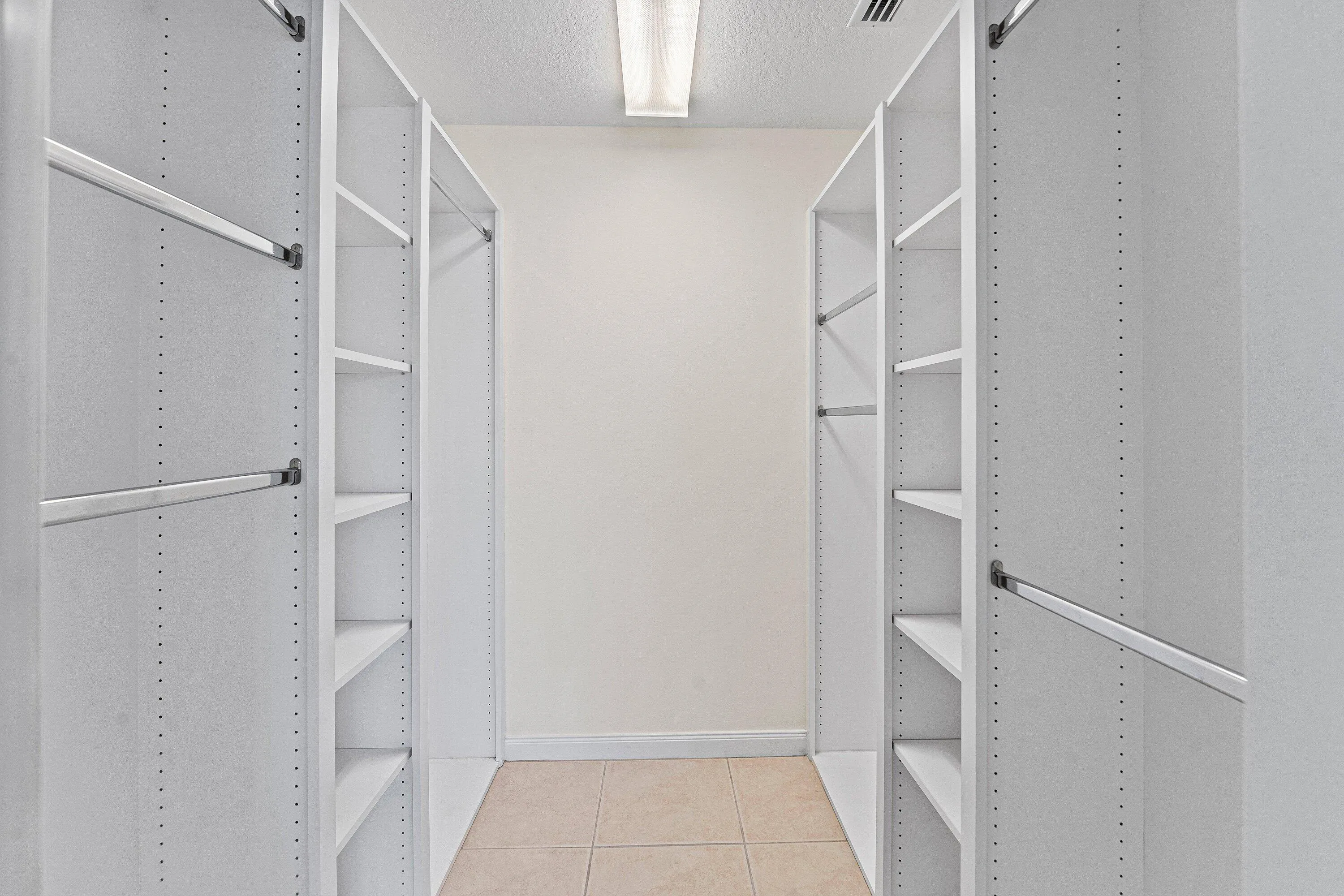 Custom closet system featuring multiple adjustable shelves and chrome hanging rods