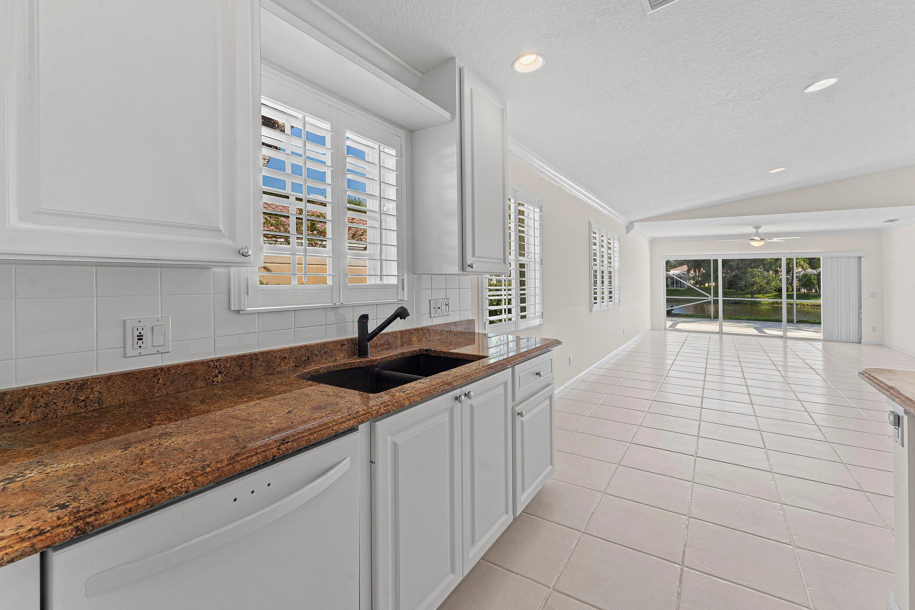 Kitchen featuring white cabinetry, granite countertops, and a black sink with a matching faucet