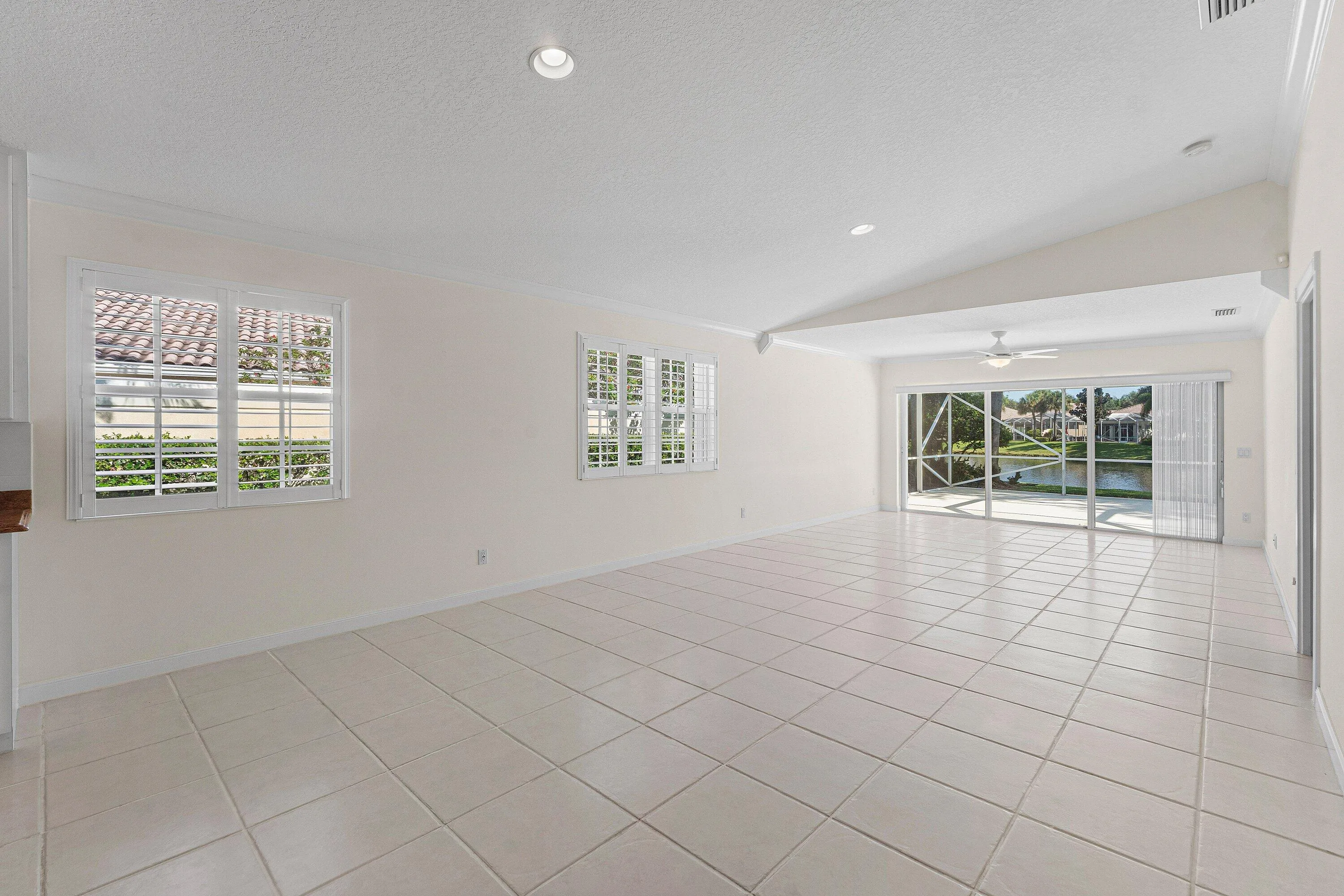 Spacious interior featuring tile flooring, vaulted ceiling, recessed lighting, and a ceiling fan