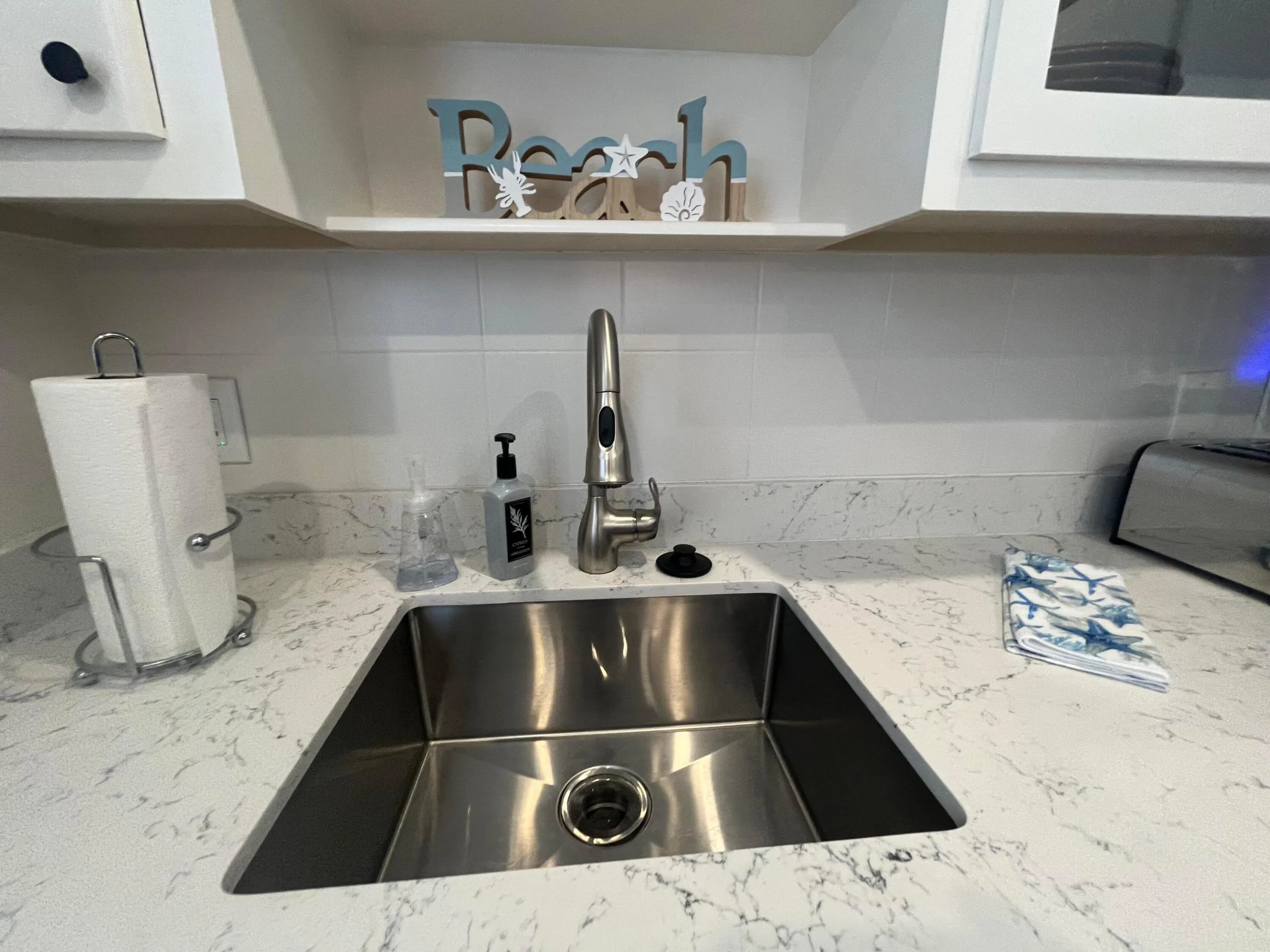 undermount stainless steel sink. Quartz countertops. Tiled backsplash