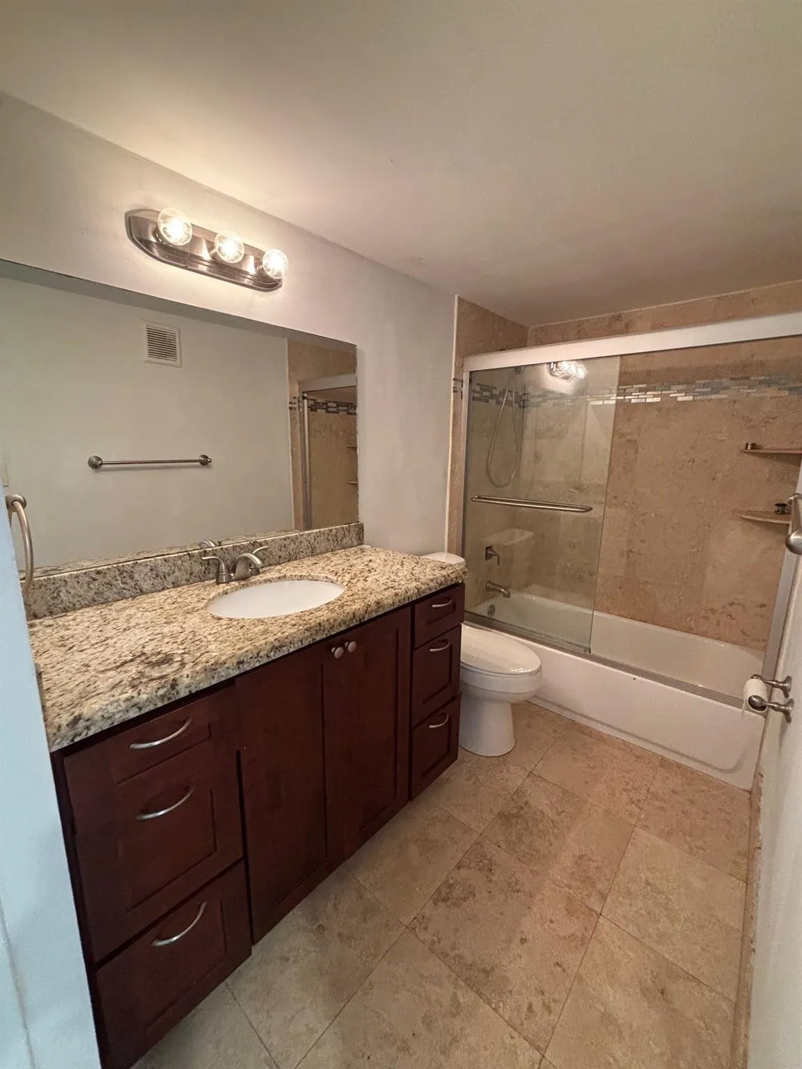 Dark wood-finish vanity with ample storage, a granite-finish countertop, and a single basin