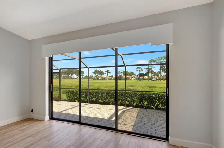 Spacious primary bedroom with wood-look laminate flooring and magnificent views of the Champion Course. Sliding glass doors open directly to the screened balcony, offering an even better vantage point to enjoy the expansive golf course views.