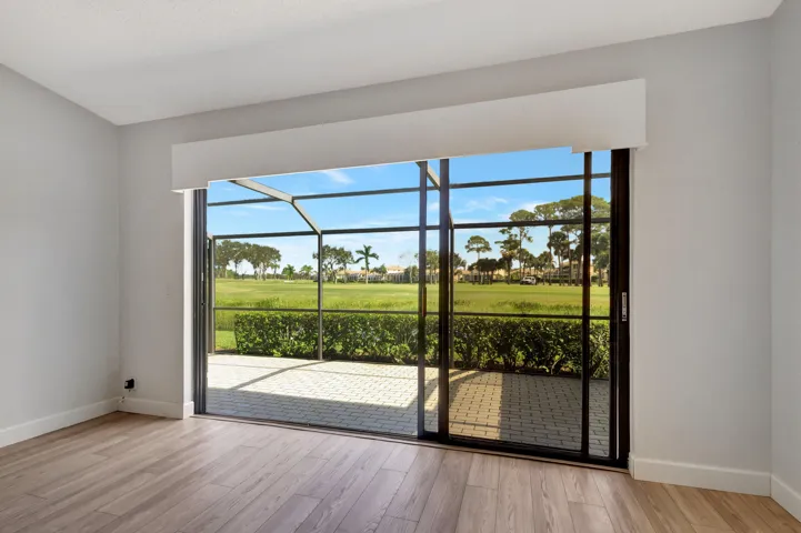 Another angle of the primary bedroom showcases the wide sliding glass doors, bringing in abundant natural light while framing the beautiful golf course views beyond.