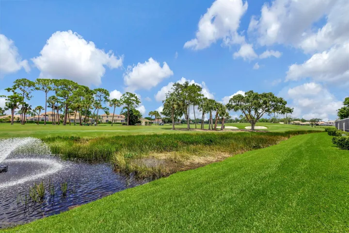 Expansive green space featuring a water feature with fountain, mature trees, and landscaping elements