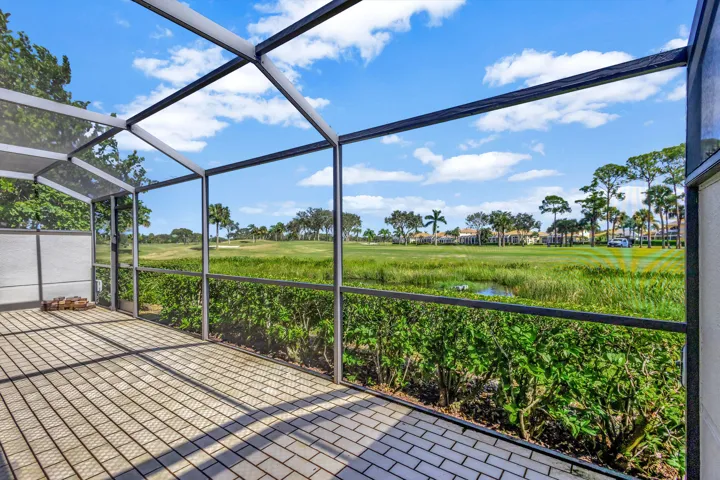 A different view from the screened patio captures the sweeping greenery of the Champion Course, surrounded by lush landscaping and tranquil golf course scenery.