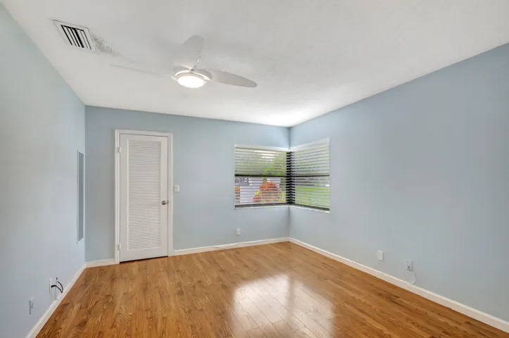 Comfortable guest bedroom featuring a soft coastal-inspired paint color and warm wood-look laminate flooring, creating a relaxed and welcoming retreat.