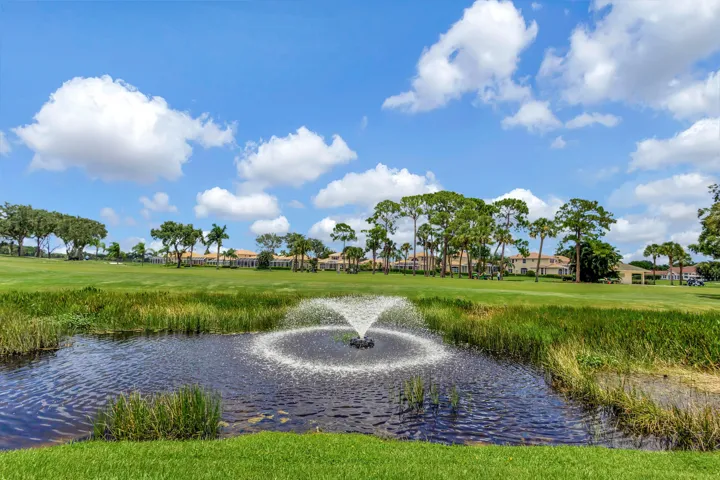 Beautifully manicured green lawn overlooking a tranquil pond accented by a decorative fountain.
