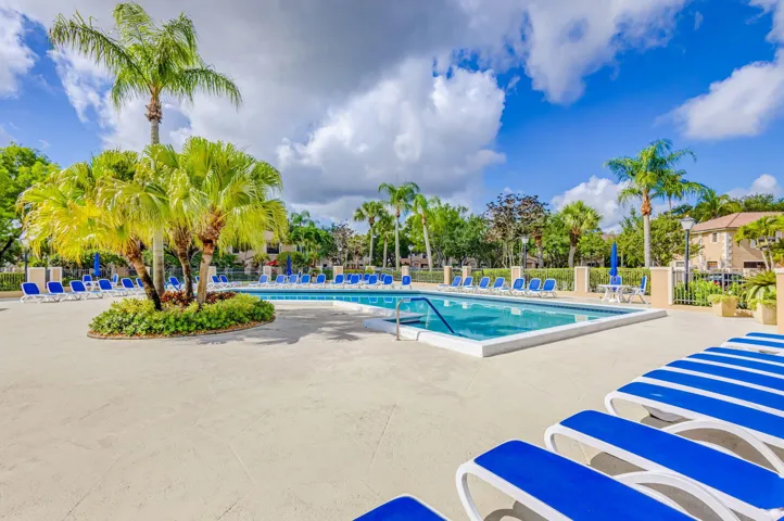 Resort-style swimming pool surrounded by a spacious concrete deck and mature palm trees