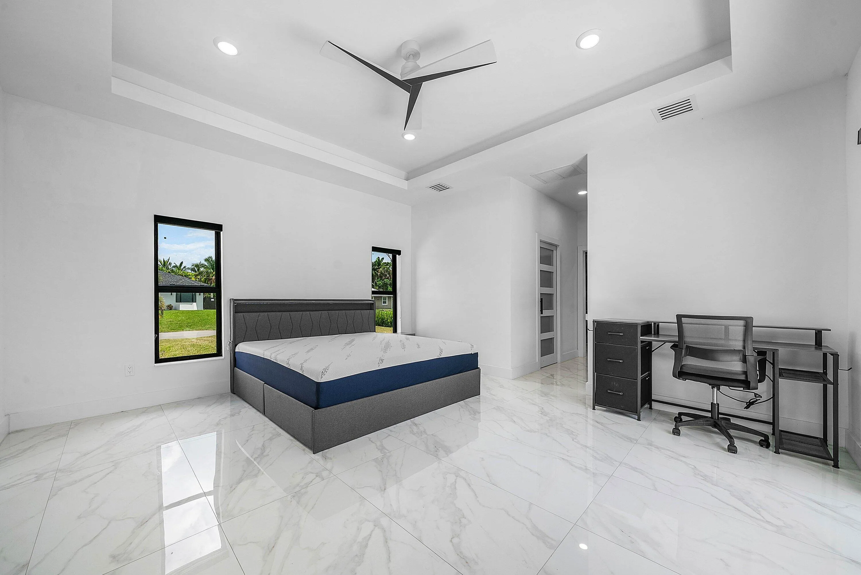 Spacious room featuring white tile flooring, tray ceiling, recessed lighting, and two windows