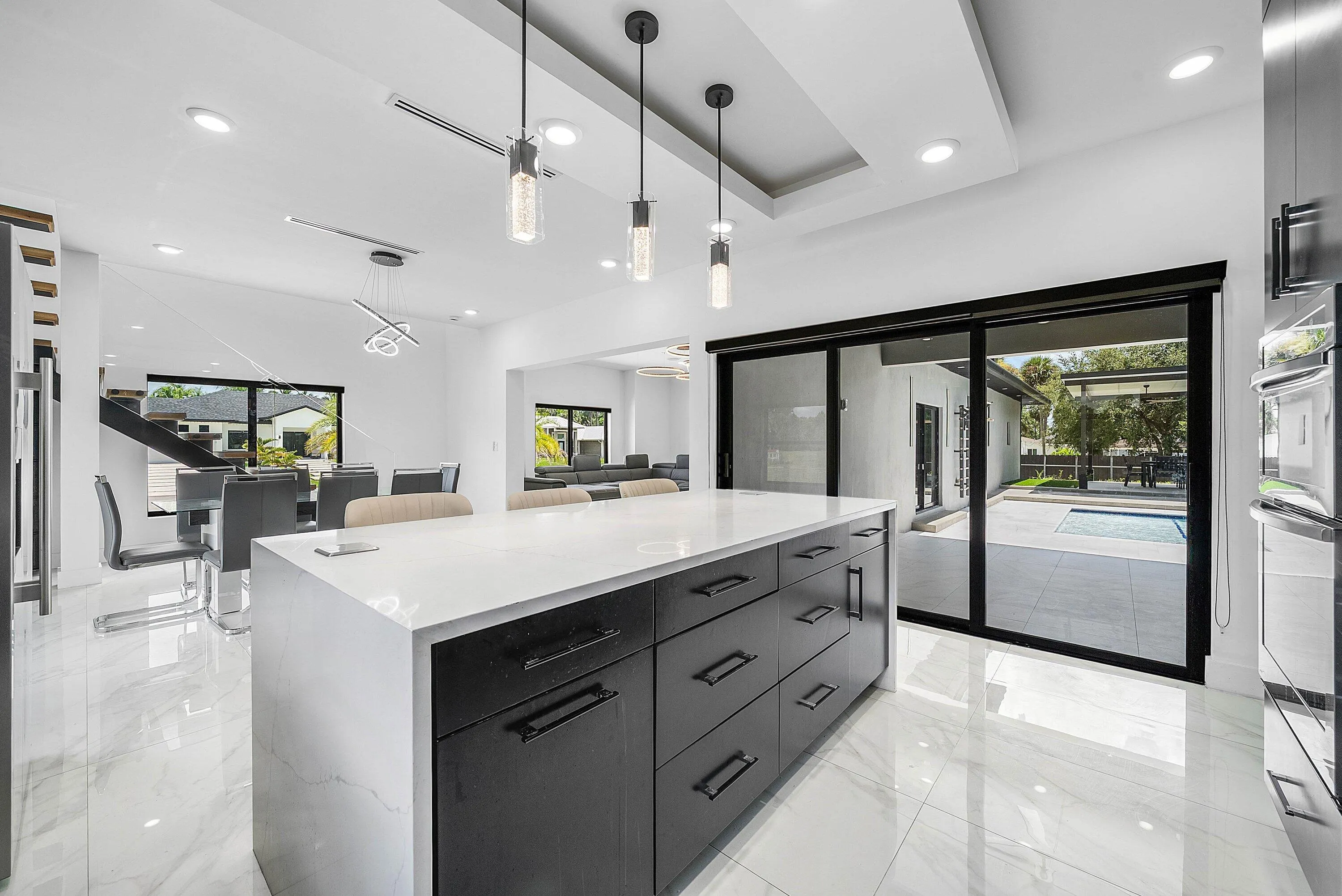 Kitchen island with a light-toned countertop, black cabinetry, and recessed lighting