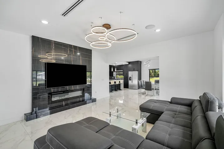 Porcelain tile flooring, built-in electric fireplace, wall-mounted television, recessed lighting, and contemporary circular chandelier