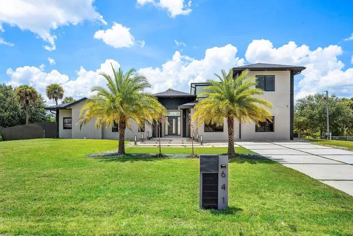 Contemporary exterior with a flat roofline, stucco finish, large windows, and a modern concrete driveway