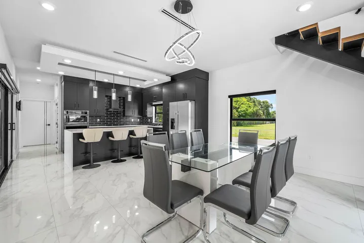 Modern kitchen featuring dark cabinetry, stainless steel appliances, a breakfast bar, and white tile flooring