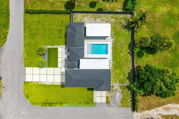 Modern residence with a dark shingle roof, integrated swimming pool, and concrete paver driveway