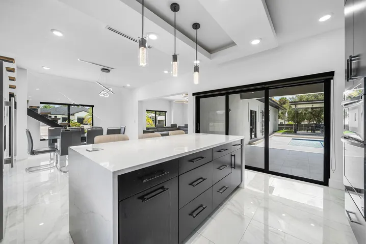 Kitchen island with a light-toned countertop, black cabinetry, and recessed lighting