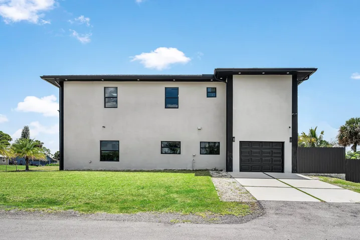 Contemporary exterior with light-colored stucco finish, dark trim details, a two-car garage, and a concrete driveway