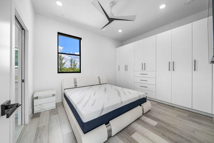 Recessed lighting, wood-finish flooring, white built-in cabinetry with drawers, and a ceiling fan with integrated lighting