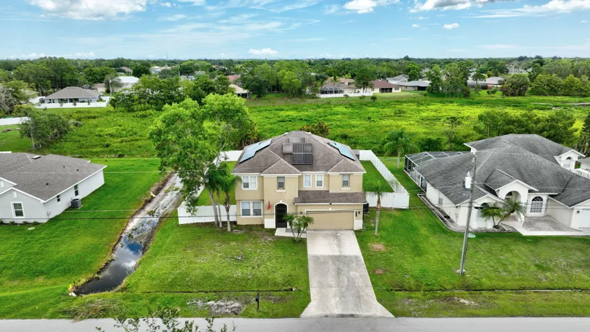Two-story residence with a beige exterior, dark roof, and solar panels