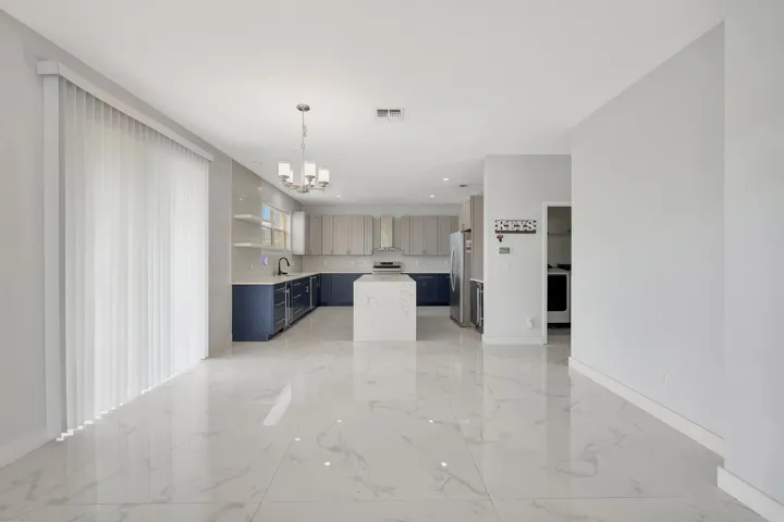 Open-concept kitchen with an island, two-tone cabinetry, and a modern chandelier