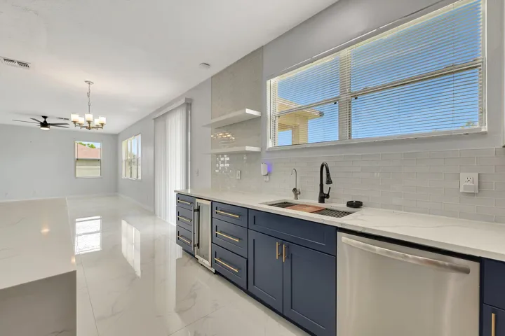 White tile flooring, navy blue cabinetry, white quartz countertops, stainless steel beverage refrigerator, and a stainless steel​​‌​​​​‌​​‌‌​‌‌​​​‌‌​‌​‌​‌​​​‌​​ dishwasher