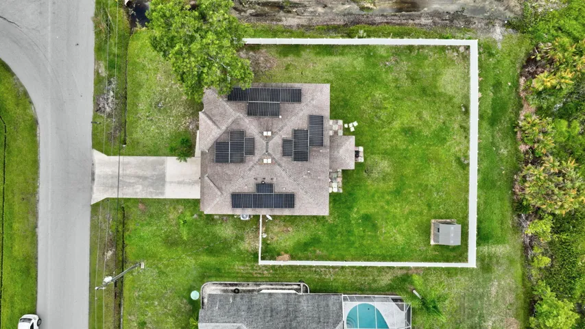 Property featuring a large lot, asphalt driveway, solar panels on the roof, and a perimeter fence