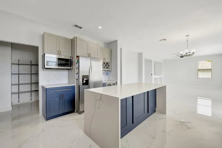 Kitchen featuring a waterfall island, stainless steel appliances, two-tone cabinetry, and large format floor tiling