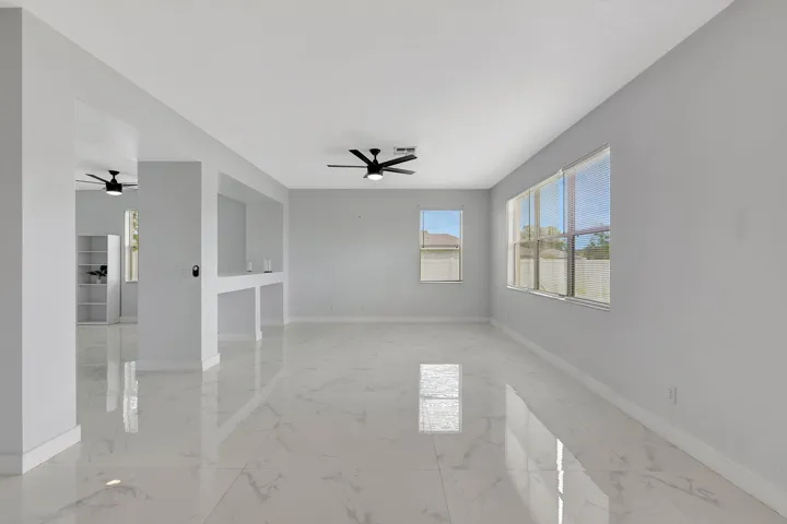 Spacious room with large windows, white walls, and polished tile flooring