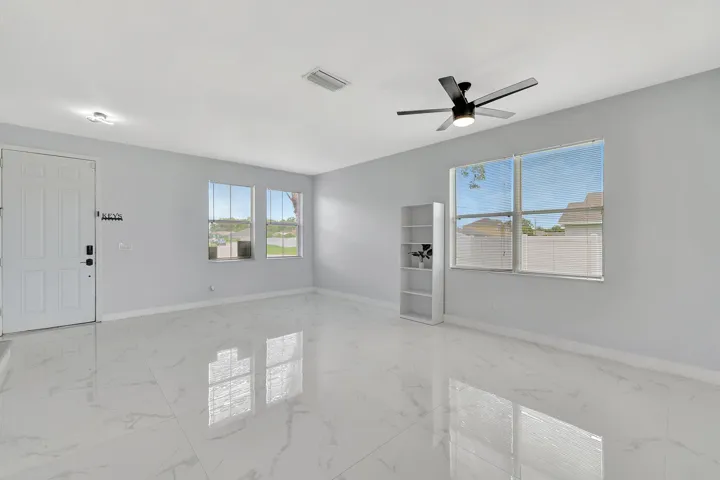 White tile flooring, multiple windows, ceiling fan with integrated lighting, recessed lighting, white entry door