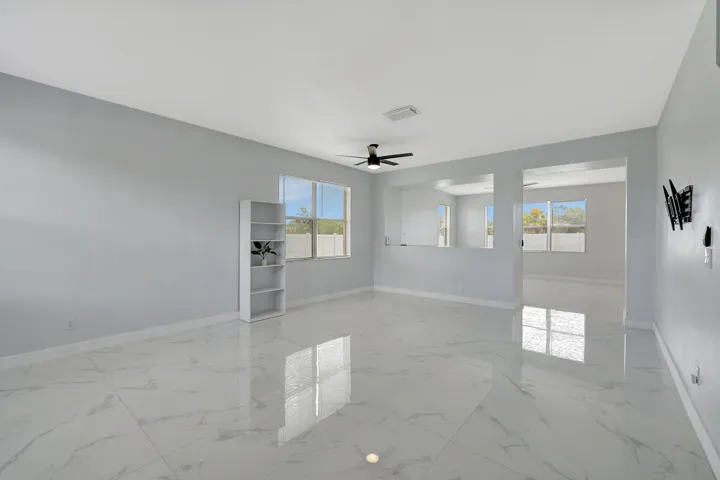 Recessed wall cutouts, windows, ceiling fan, and large format polished tile flooring