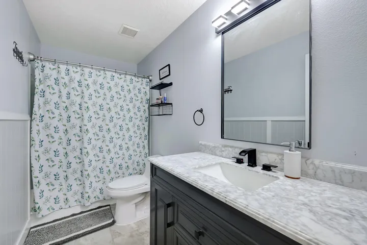 Single vanity with a white rectangular sink, matte black faucet, and stone countertop