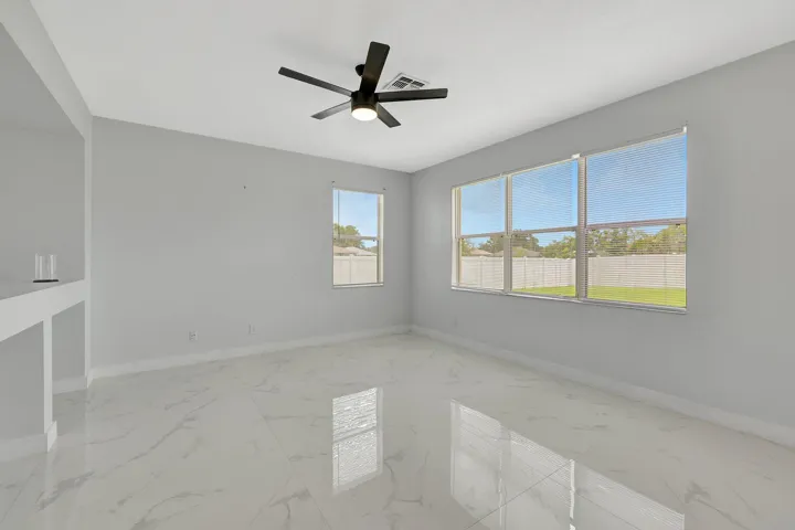 White tile flooring, built-in shelving, multiple windows, and a ceiling fan with integrated lighting