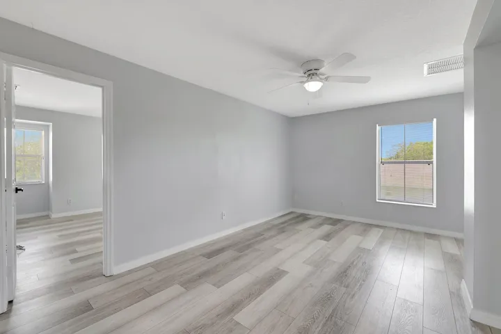 Wood-finish flooring throughout, light gray wall paint, and a ceiling fan with integrated lighting