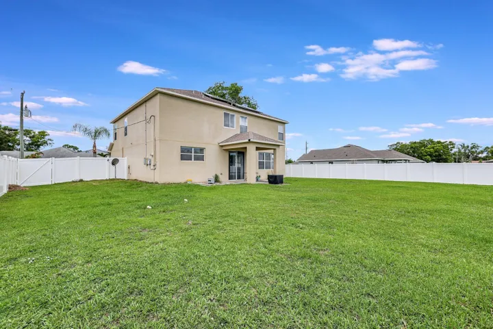 Expansive green lawn with a white vinyl privacy fence enclosing the property
