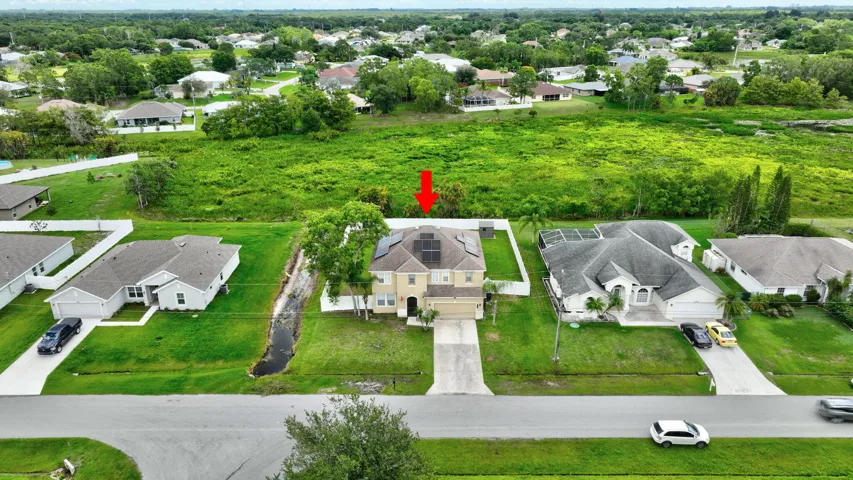 Two-story residence featuring a concrete driveway, attached garage, and solar panels on the roof