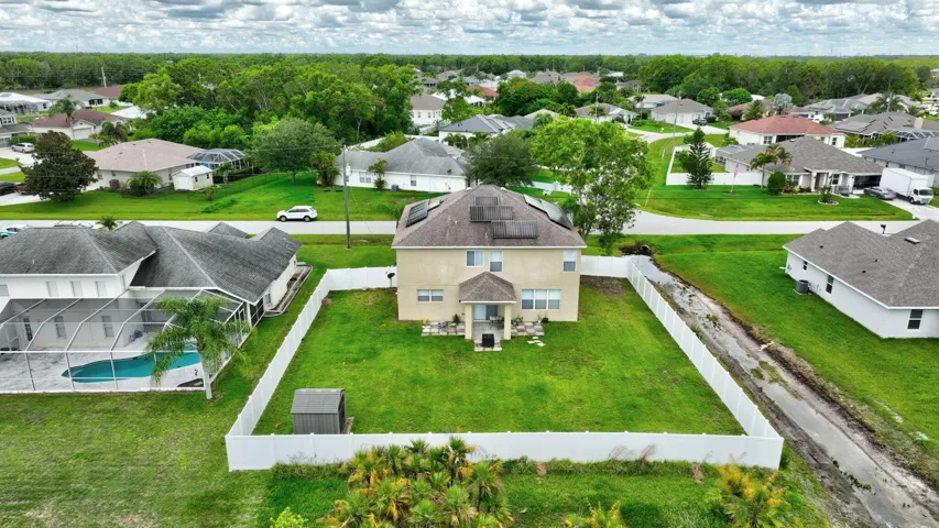 Two-story stucco exterior with a covered entry, established lawn, and a white privacy fence