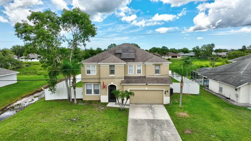 Two-story residence featuring a two-car garage, front yard landscaping, and a fenced backyard