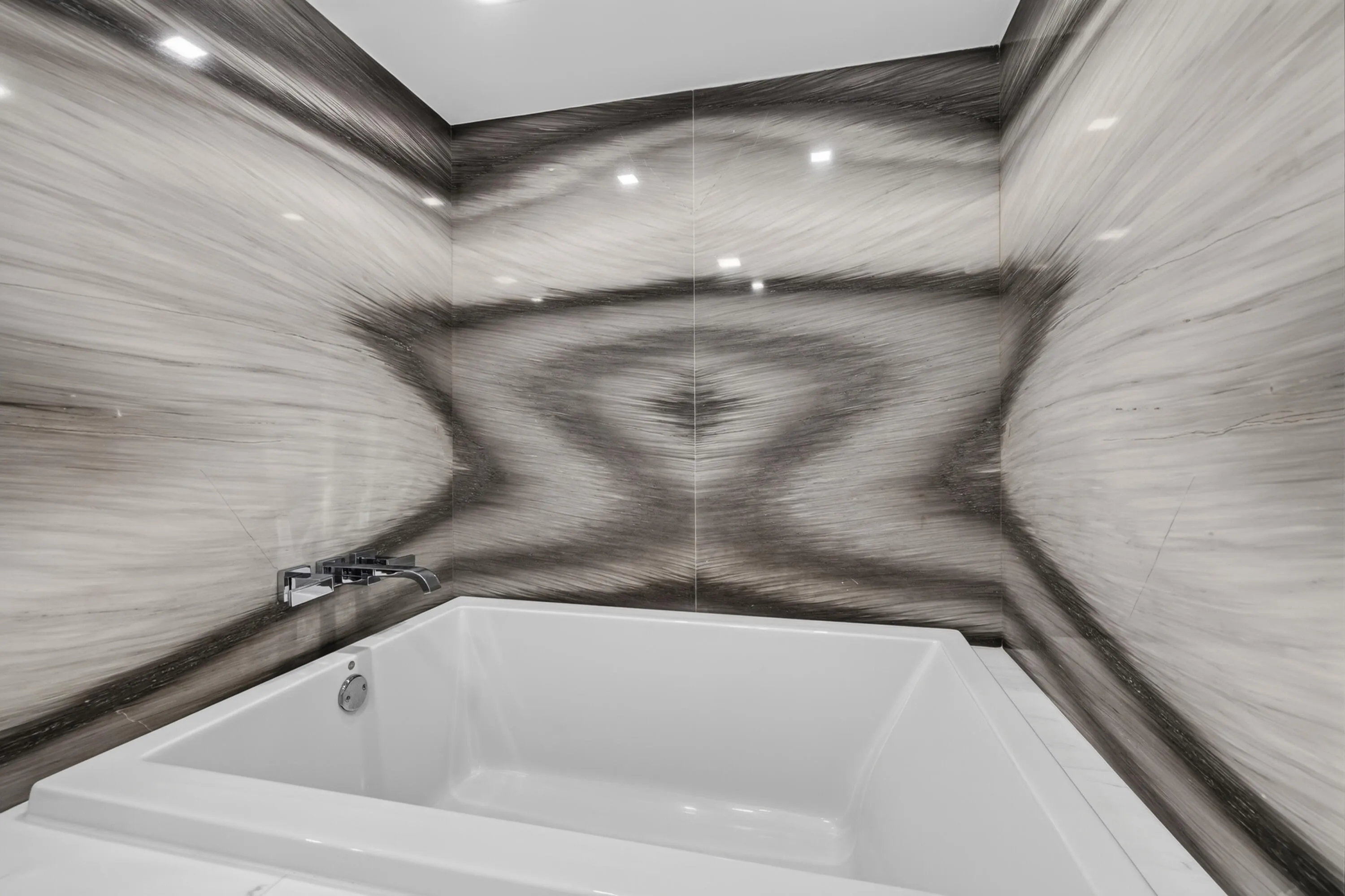 Relax in the deep soaking tub surrounded by dramatic book-matched stone-look walls and refined fixtures.