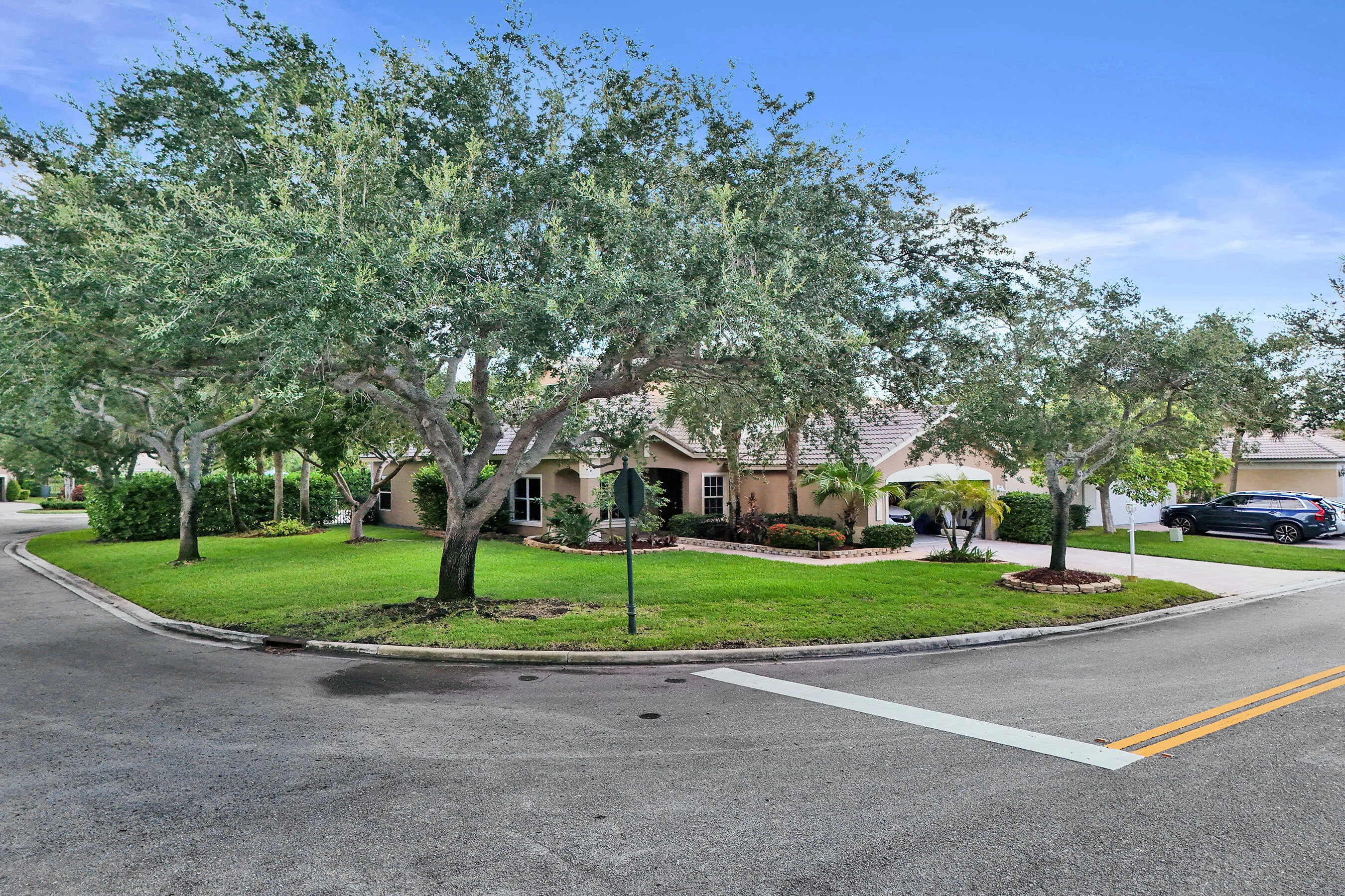 Corner lot residence featuring a well-manicured lawn, mature trees, and established landscaping