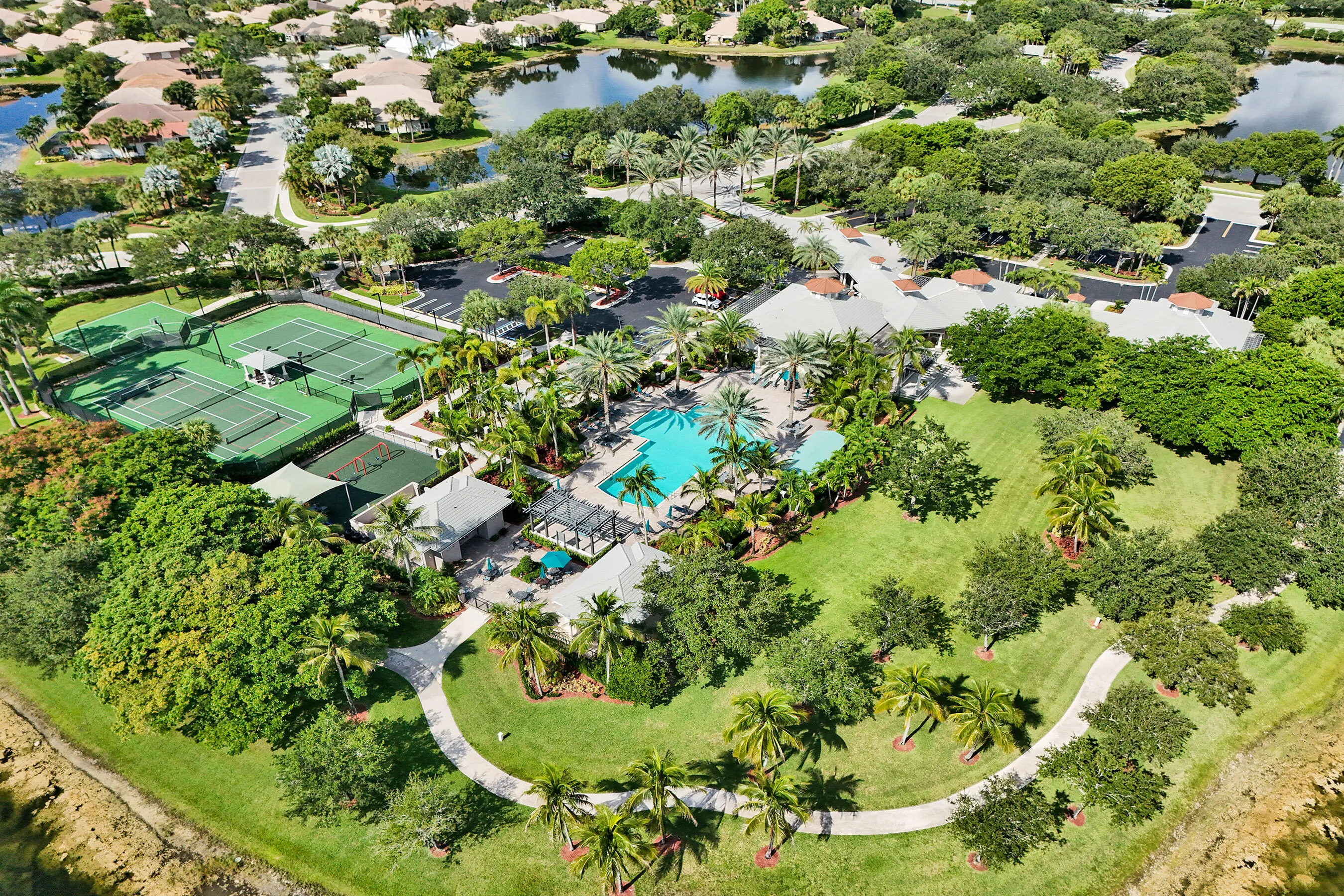 Community amenities featuring multiple tennis courts, a swimming pool, a clubhouse, and walking paths surrounded by extensive landscaping
