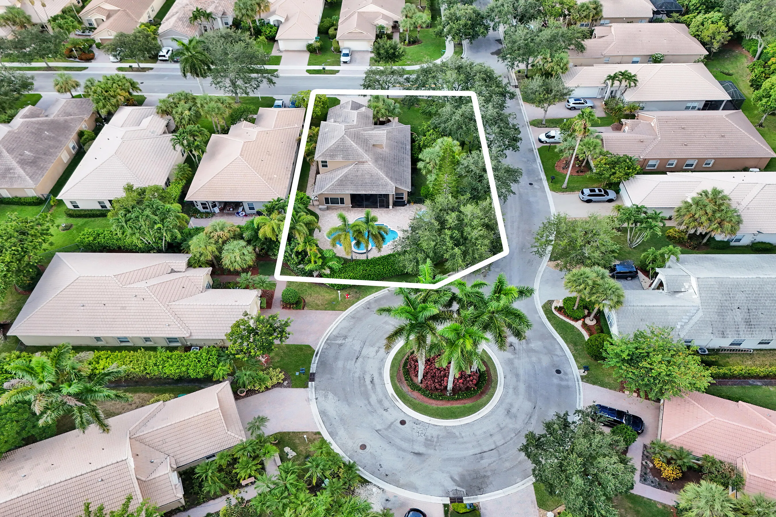 Residential property featuring a screened-in pool, lush landscaping, and a paver patio